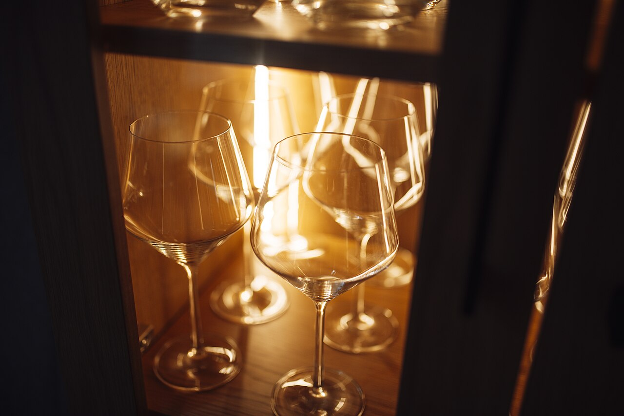 Warm-lit glassware display in a wooden cabinet