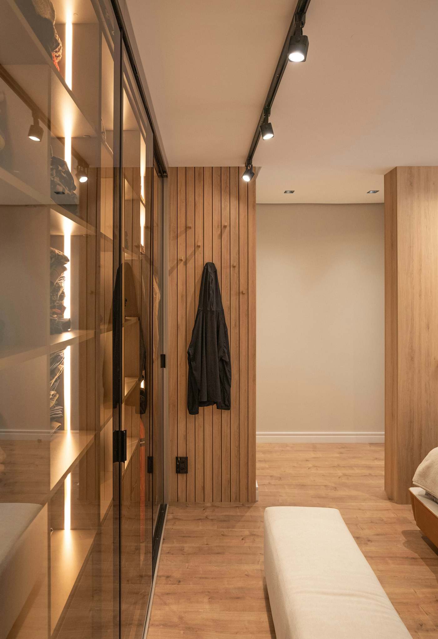 Warmly lit shelves behind glass wardrobe doors